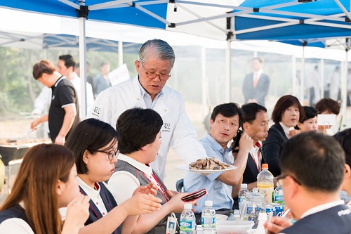 지난달 31일 최신원 SK네트웍스 회장(좌측 네 번째)이 SK매직 화성공장에서 비비큐 파티를 열고 직원들에게 직접 구운 고기를 전달하고 있다. SK네트웍스 제공 