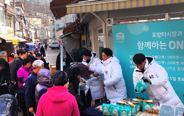 △KT 직원이 15일 서울 서대문구 포방터시장에서 시장을 찾은 지역민들에게 장바구니, 온쫄면, 핫팩, 온음료 등을 나눠주고 있다/사진=KT