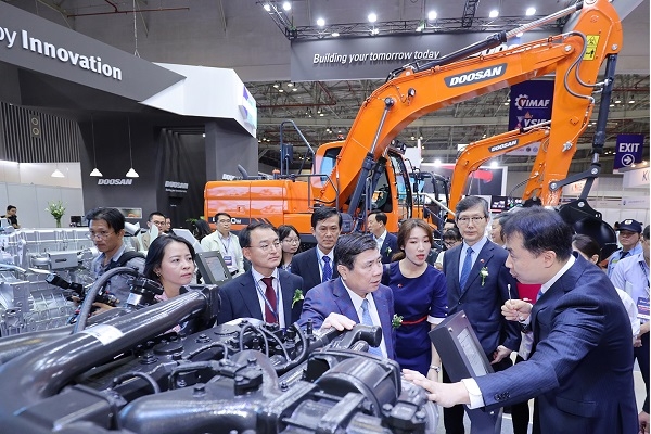 두산인프라코어 관계자가 응우옌 탄 퐁 호치민 인민위원회 위원장(오른쪽 두번째)에게 GL11K 차량용 엔진 모델을 설명하고 있다. (사진=두산인프라코어.)