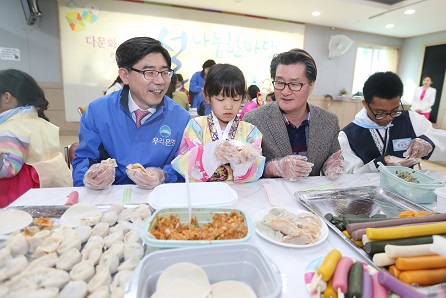 27일 서울 관악구 소재 관악노인복지관에서 우리은행 이광구 우리은행장(사진 왼쪽)과 유종필 관악구청장(사진 오른쪽)이 다문화가족 어린이와 함께 다가오는 설을 맞이하여 어려운 이웃들에게 전달할 만두를 빚고 있다.