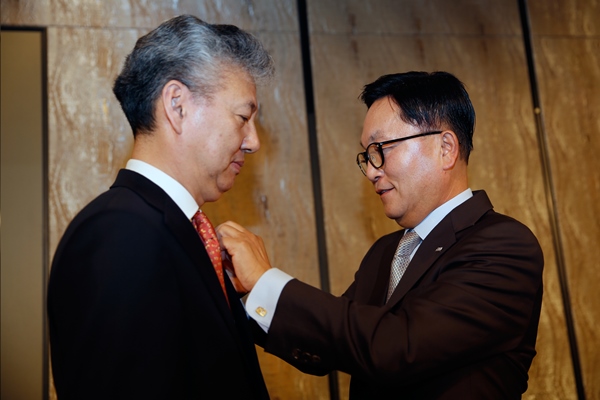 박현주 미래에셋 회장(오른쪽)이 홍성국 대우증권 사장에게 그룹 배지를 달아주고 있다(제공=미래에셋증권)