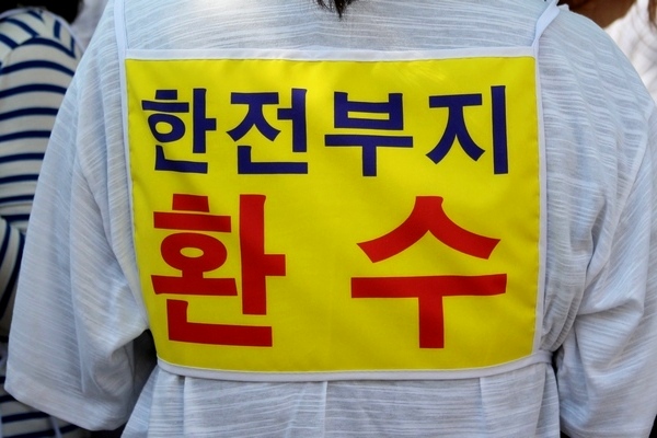 이날 집회에 참석한 한 신자가 ‘한전 부지 환수’ 글귀가 적힌 띠를 등에 두르고 있다. 정수남 기자