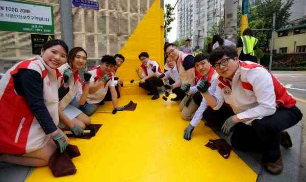 기아차 임직원들이 보행자 사고 예방을 위해 초등학교 인근 횡단보도 앞에 노란색의 미끄럼 방지 재질의 ‘옐로 카펫’을 설치하고 있다.