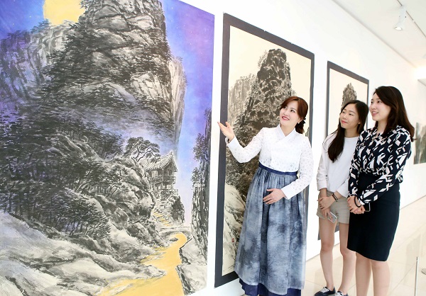 갤러리H 관계자가 류재춘 작가의 작품 ‘달빛아래’에 대해 설명하고 있다. 현대백화점제공
