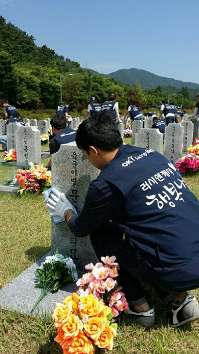 △아프로서비스그룹 직원이 국립대전현충원 묘역 비석을 닦고있다./사진제공=OK저축은행