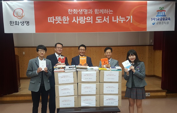 △김남수 TRI 서울지역단장(좌측에서 두번째), 강재준 한화생명 파트장(좌측에서 세번째), 임근창 보라중학교 교장(좌측에서 네번째)이 보라중학교 학생(양 옆)들과 함께 기증도서를 들고 활짝 웃고 있다./사진제공=한화생명