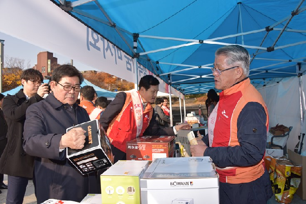 김기동 광진구청장(좌)이 SK행복나눔바자회이 열리는 건대입구 분수광장에서 판매되는 상품을 살펴보며 최신원 SK네트웍스 회장의 설명을 듣고 있다. SK네트웍스 제공