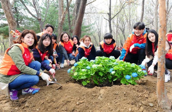 △ SK건설 임직원 가족봉사단이 화단에 수국을 심고 기념촬영을 하고 있다. SK건설 제공