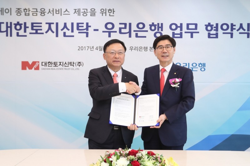 박성표 대한토지신탁 대표이사(사진 오른쪽)와 이광구 우리은행장이 13일 우리은행 본점에서 업무협약서를 들고 기념촬영을 하고 있다.