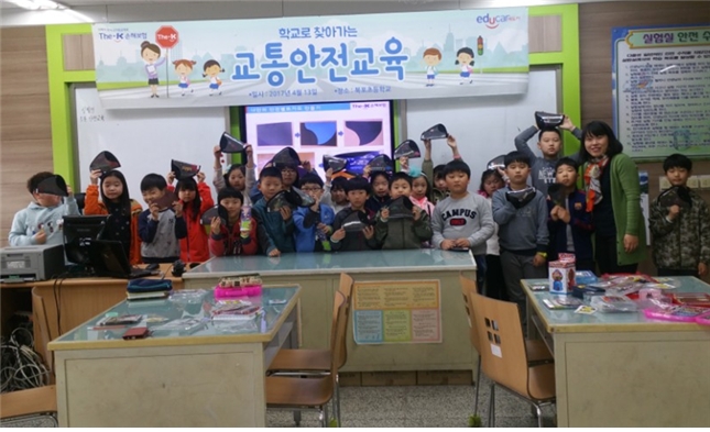△서해 백령도에 위치한 북포초등학교의 1~3학년 학생들이 더케이손해보험의 교통안전교육을 마치고 직접 만든 '나만의 안전벨트가드'를 들고 기념촬영을 하고 있다./사진제공=더케이손해보험