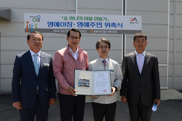 △이완섭 서산시장(좌측 두 번째)이 이윤배 NH농협손해보험 대표이사(좌측 세 번째)에게 명예이장 위촉장을 전달하고 최영균 팔봉면장(좌측 첫 번째), 안동일 뱅길이 마을 이장(우측 첫 번째)과 함께 기념촬영을 하고 있다.
