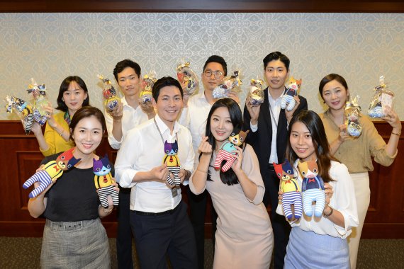△지난 28일 KB증권 여의도 본사에서 직원들이 직접 만든 양말인형을 들고 기념촬영을 하고 있다.