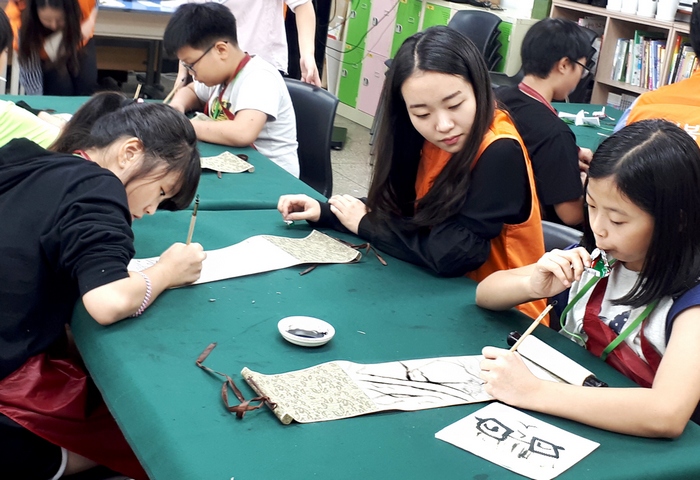 한화투자증권 임직원들이 지난 15일 한화예술더하기 전통문화예술교육 도움을 주고있다.