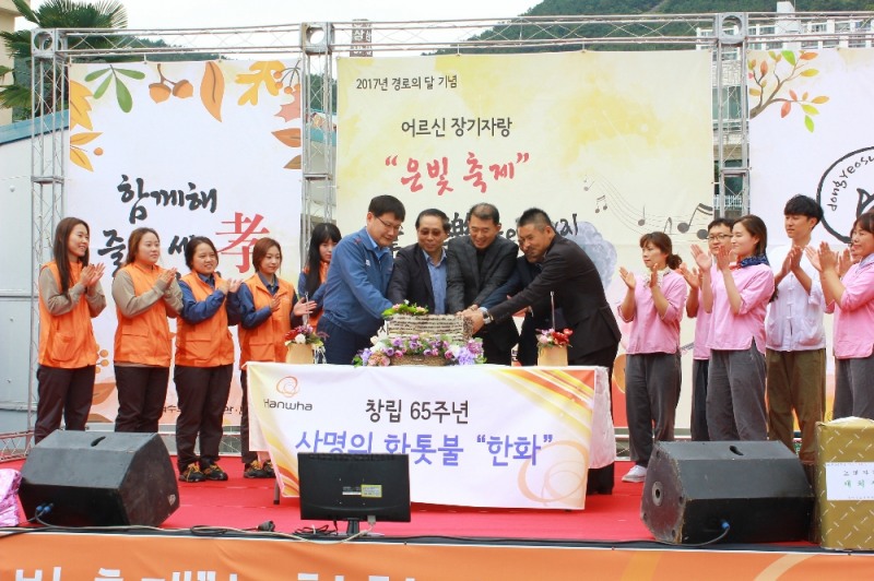 △㈜한화/방산 여수사업장 임직원과 관계자들이 동여수노인복지관에서 한화그룹의 창립65주년과 노인의 날을 기념하며 시루떡 절단식을 하고 있다 /사진제공=한화그룹