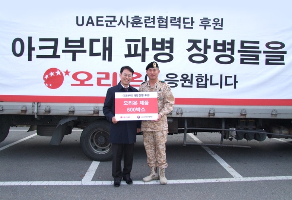 황순일 오리온 CSR실천부문장과 김기정 UAE군사훈련협력단장 중령이 오리온 제품 600박스 전달식을 갖고 기념촬영을 하고 있다. 오리온그룹 제공