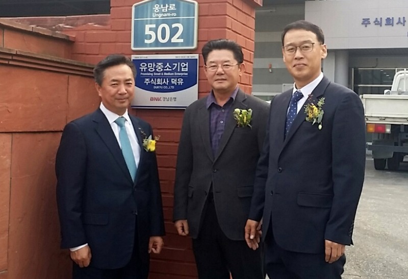 △BNK경남은행 김형동 부행장(사진 왼쪽)이 ㈜덕유를 방문해 류덕형 대표이사(가운데) 등 관계자와 '유망중소기업 현판식'을 갖고 있다. /사진=BNK경남은행