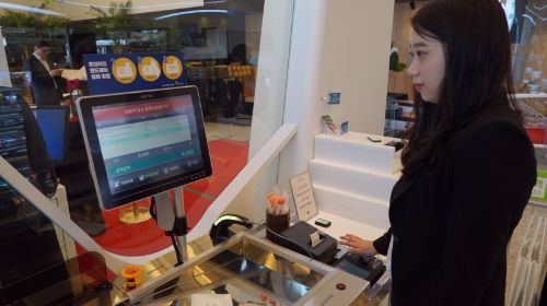 잠실 롯데월드타워에 위치한 세븐일레븐 시그니처 점포에서 한 고객이 정맥기술을 활용한 핸드페이로 결제를 진행하는 모습. 코리아세븐 제공