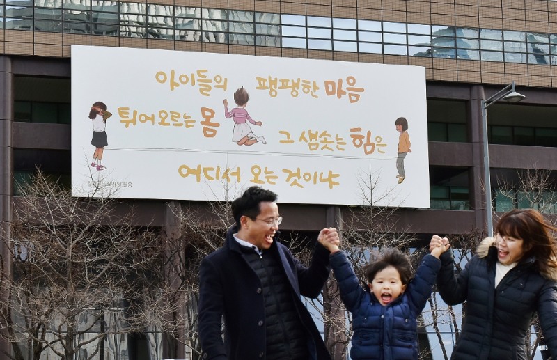 △5일 한 가족이 교보생명 광화문글판 '봄편'이 내걸린 광화문 교보생명빌딩 주변을 걷고 있다. / 사진=교보생명