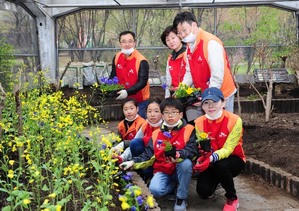 SK건설 임직원 가족봉사단이 화단에 꽃을 심고 기념촬영을 하고 있다. / 사진=SK건설.