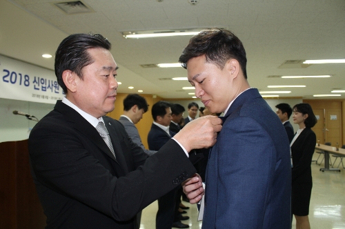 김인규 하이트진로 사장(좌)이 신입사원에게 뱃지를 수여하고 있다. 하이트진로 제공