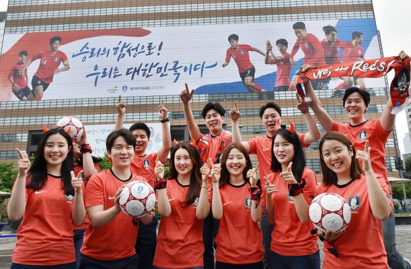 △교보생명 직원들이 14일 광화문 교보생명빌딩에 설치된 축구 국가대표팀의 선전을 응원하는 초대형 래핑(Wrapping)을 배경으로 '2018 러시아 월드컵'의 승리를 기원하는 응원전을 펼치고 있다. / 사진=교보생명