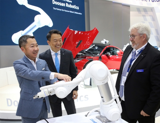 박정원 두산그룹 회장(왼쪽)이 두산로보틱스 부스에서 독일 로봇시장의 한 딜러 업체 대표(오른쪽)와 협동로봇에 대해 이야기를 나누고 있다. 사진=두산그룹.