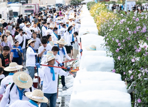 지난 11일 서울 광화문 광장에서 개최된 ‘2018 한여름밤의 눈조각전’에서 크라운-해태제과 임직원이 동시에 눈블럭을 조각하고 있는 모습. 크라운해태 제공