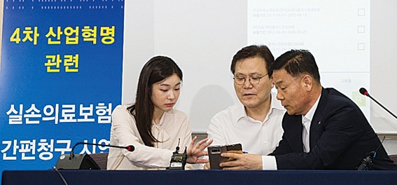 ▲ 최종구 금융위원장(가운데)과 김연아 전 국가대표 피겨선수(왼쪽)가 실손의료보험 간편청구 앱을 시연하고 있다. 사진=금융위원회