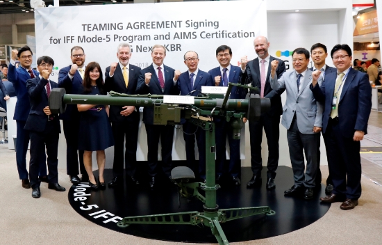 13일 대한민국 방위산업전 ‘DX-KOREA’ 전시장에서 LIG넥스원 김지찬 대표(앞줄 우측5번째)와 KBR社의 랍 호켓(Mr. Rob Hawketts) 부사장(앞줄 우측 6번째) 등 양사 관계자들이 최신형 피아식별장비인 모드(Mode)-5가 탑재된 휴대용 지대공 유도무기 신궁 앞에서 기념사진을 촬영하고 있다. 사진=LIG넥스원.