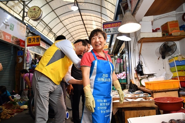 조성완 사장이 상가 상인에게 전기안전 캠페인 문안이 새겨진 앞치마를 매어주고 있다. 출처 : 한국전기안전공사.