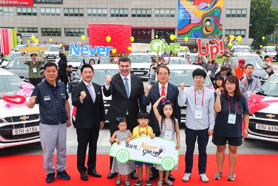 19일 한국지엠한마음재단이 부평아트센터(인천 부평구 소재)에서 ‘쉐보레 네버 기브 업’ 차량 기증식을 개최하고 쉐보레 네버 기브 업 캠페인을 통해 선정된 30 가정에 쉐보레 스파크 30대를 전달했다. 사진은 카허카젬(Kaher Kazem) 한국지엠 사장(가운데), 전광렬 초록우산 어린이재단 홍보대사(가운데 왼쪽), 임한택 금속노조 한국지엠지부 지부장(맨 왼쪽), 이제훈 초록우산 어린이재단 회장(가운데 오른쪽), 수혜자 가족 이영현씨(37세, 여, 맨 오른쪽) 등 이 날 행사에 참석한 참석자들이 함께 웃고 있는 모습. 사진=한국지엠.