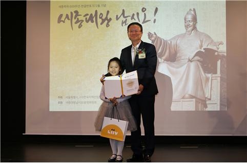 △신홍섭 KB저축은행 대표가 이서현 학생(왼쪽)에게 세계어린이한글손글씨대회 특선상을 시상한 후 기념촬영을 하고 있다./사진=KB저축은행