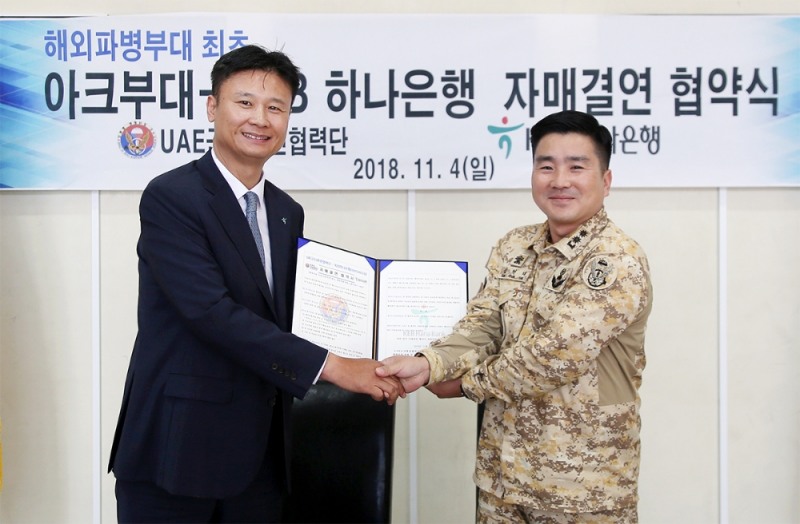 KEB하나은행은 4일 아랍에미리트에 파병되어 있는 대한민국 육군 UAE군사훈련 협력단(아크부대)과 국고금 관리 및 각종 금융서비스 지원을 위한 자매결연을 체결하였다. 자매결연 체결 후 노영준 KEB하나은행 아부다비지점장(사진 왼쪽)과  김현태 UAE군사훈련협력단장(중령)이 기념사진 촬영을 하고 있다. / 사진= KEB하나은행