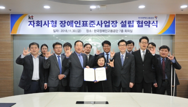 △경영관리부문장 신현옥 전무(앞줄 좌측 세번째)와 한국장애인고용공단 조종란 이사장(앞줄 좌측 네번째)이 협약식 행사장에서 관계자들과 함께 수화로 '사랑'을 나타내며 기념촬영을 하고 있는 모습/사진=KT