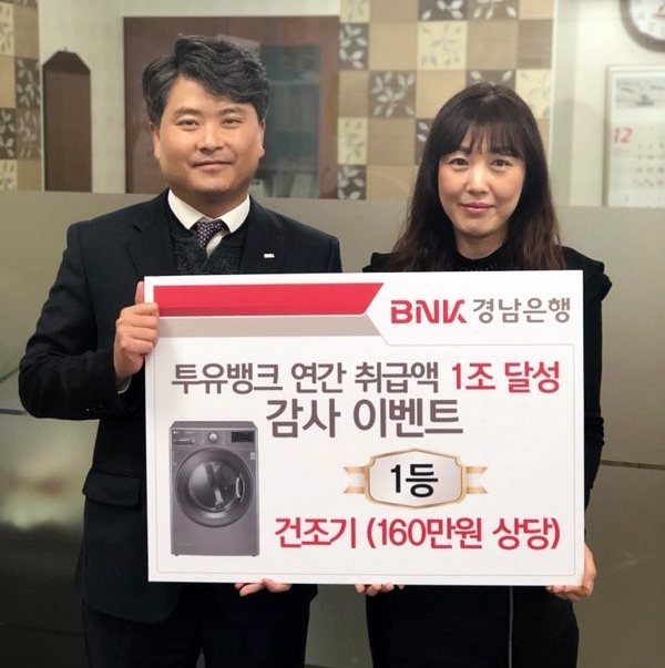 △BNK경남은행 율하지점 홍응일 영업점장(사진 왼쪽)이 비대면 금융상품 연간 취급액 1조원 돌파 이벤트 1등 당첨자에게 ‘160만원 상당의 의류 건조기 증서’를 전달하고 있다./사진=BNK경남은행