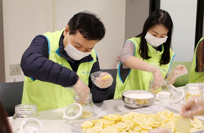 봉사활동에 참여한 윤규선 하나캐피탈 대표이사(사진 왼쪽)이 '사랑봉사단' 직원들과 함께 레몬청을 만들고 있다. / 사진 = 하나캐피탈