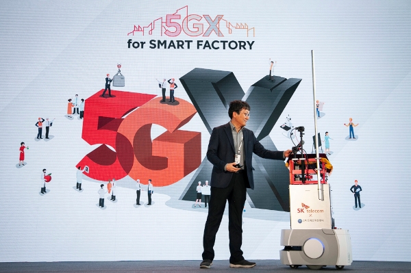 △장홍성 SK텔레콤 IoT/Data사업단장이 5G 소형 자율주행로봇이 전달하는 마이크를 받고 있다/사진=SK텔레콤