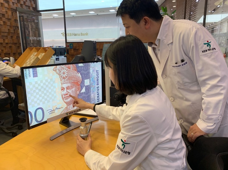 KEB하나은행 위변조대응센터 직원들이 전문장비로 말레이시아 화폐를 감정하고 있다. / 사진= KEB하나은행