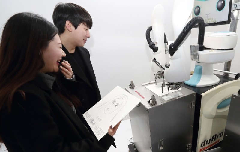 △KT 홍보모델들이 초상화 로봇을 체험해보고 있다/사진=KT