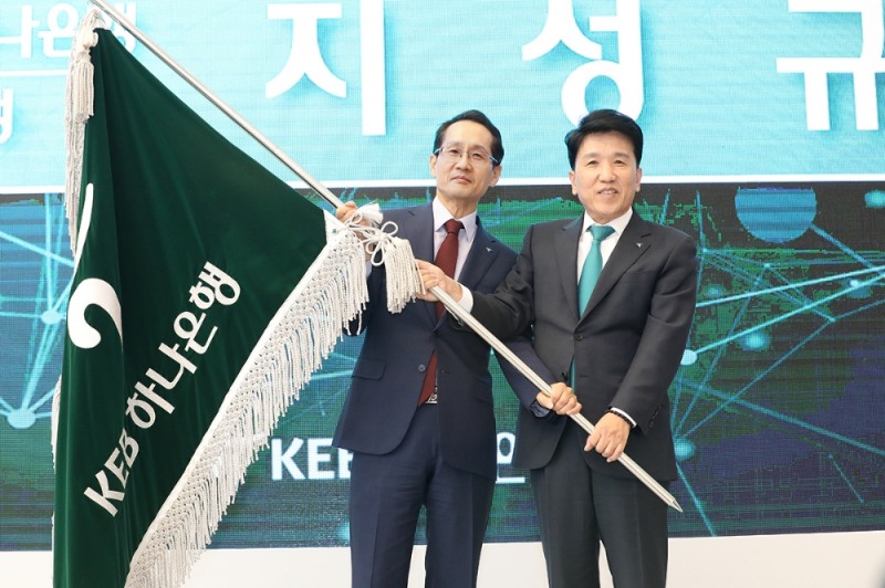 21일 KEB하나은행 을지로 신사옥에서 진행된 이취임식에서 지성규 신임 KEB하나은행장(사진 왼쪽)과 함영주 전임 KEB하나은행장(사진 오른쪽)이 은행 깃발을 함께 들고 힘차게 흔들고 있다. / 사진= KEB하나은행