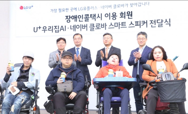 △류창수 LG유플러스 스마트홈상품그룹장 상무(뒷줄 오른쪽에서 두번째), 민병찬 서울시설공단 복지경제본부 본부장(뒷줄 오른쪽에서 세번째), 정석근 네이버 서치앤클로바 CIC 리더(뒷줄 오른쪽 첫번째), 권순만 서울시설공단 장애인콜택시운영처장(뒷줄 오른쪽에서 네번째)이 U+우리집AI 스피커를 전달받은 지체장애인과 함께 기념촬영하고 있다/사진=LG유플러스