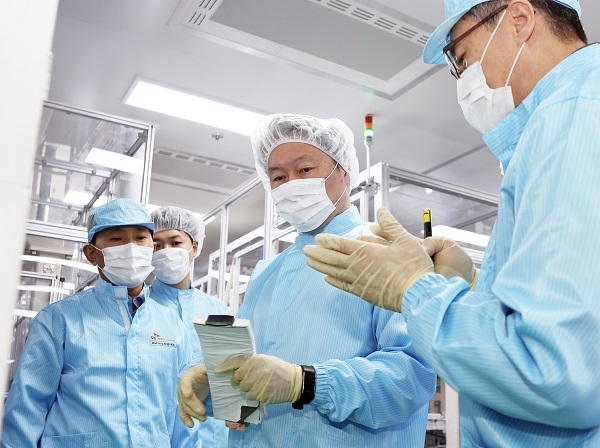 배터리 셀을 든 최태원 회장(가운데)이 김진영 배터리생산기술본부장(오른쪽)으로부터 이에 대한 설명을 듣고 있다. (사진=SK이노)