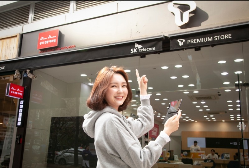 △SKT 모델이 공식 인증 대리점 앞에서 V50 기기를 사용하는 모습을 시연하고 있다/사진=SKT