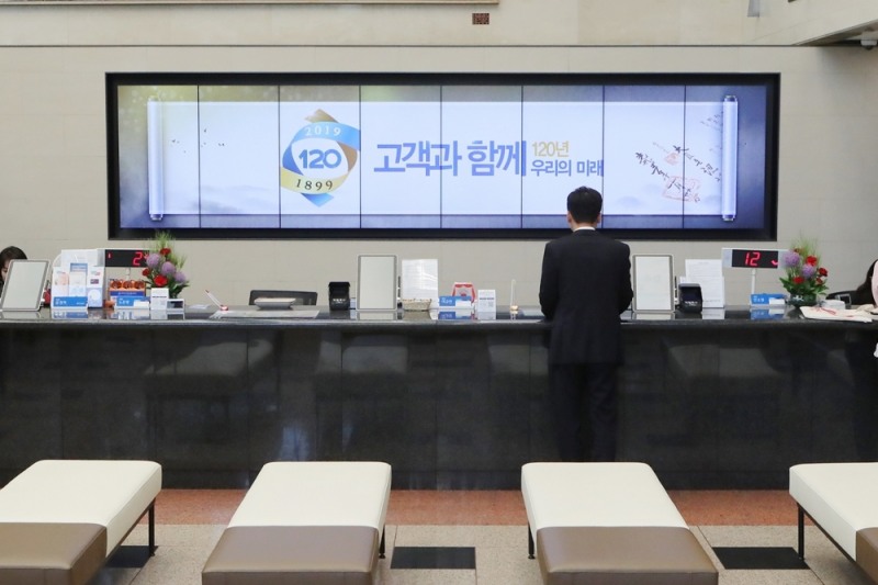 고객들이 디지털사이니지가 설치된 우리은행 본점영업부에서 업무를 처리하고 있다./사진=우리은행