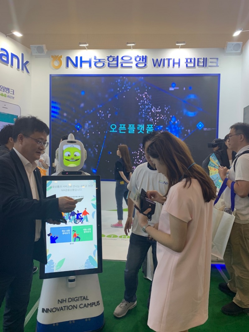 NH농협은행이 코리아 핀테크 위크 2019에서 로봇 기반 키오스크를 시현하고 관계자와 이야기를 나누고 있다.