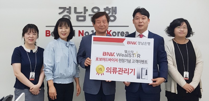 BNK경남은행 서면지점 이은 영업점장(오른쪽 두번째)이 BNK웰스타로보 이벤트 1등 당첨자(오른쪽 세번째)에게 ‘200만원 상당의 의류 관리기 증서’를 전달하고 있다./사진=경남은행