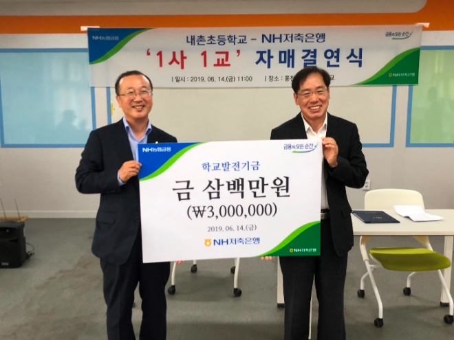 14일 강원도 홍천군 내촌초등학교에서 진행된 '내촌초등학교-NH저축은행 1사 1교 자매결연식'에서 NH저축은행 김건영 대표(왼쪽)가 내촌초등학교 한만식 교장(오른쪽)에게 학교발전기금을 전달하고 있다. / 사진 = NH농협금융