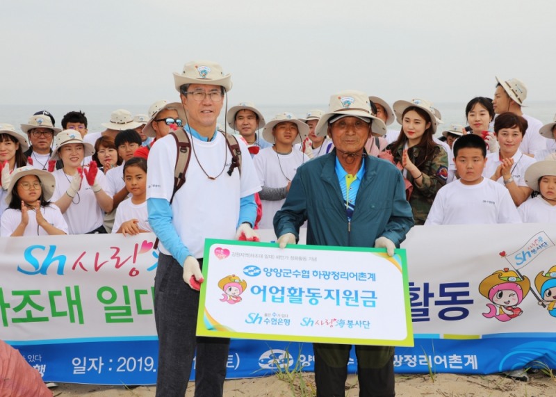 15일 강원지역 해안정화활동을 마친 이동빈 수협은행장이 김의남 하광정리어촌계장에게 어업활동지원금을 전달하고 있다./사진=수협은행