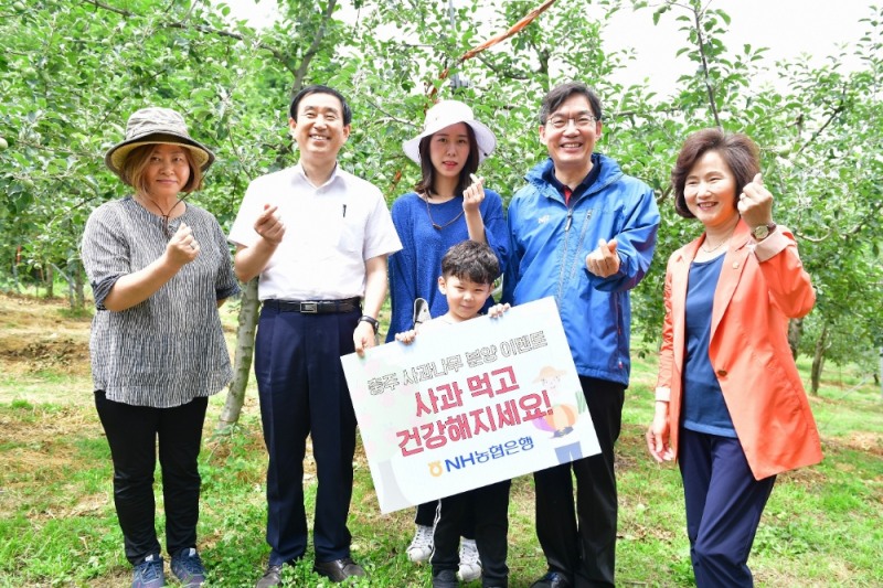 이대훈 은행장(오른쪽 두번째), 조길형 충주시장(사진 왼쪽 두번째), 허영옥 충주시의장(오른쪽 첫번째)이 고객과 함께 사과나무 앞에서 기념촬영을 하고 있다./사진=농협은행