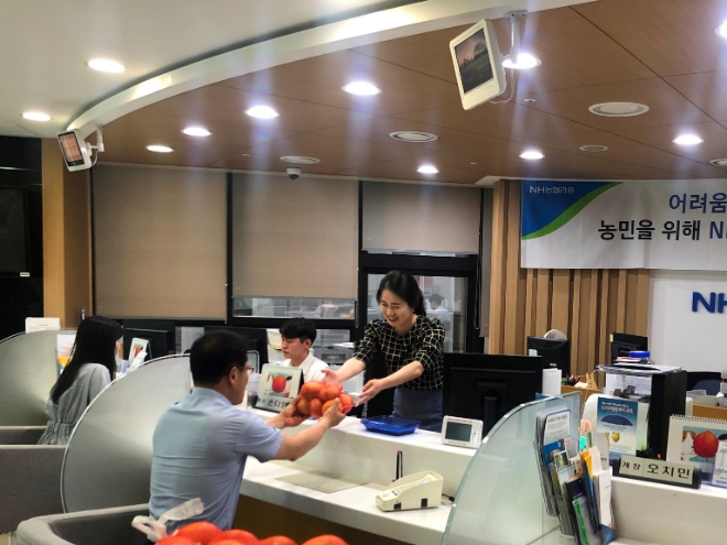 NH저축은행 직원이 고객에게 양파를 건네고 있다. / 사진 = NH저축은행